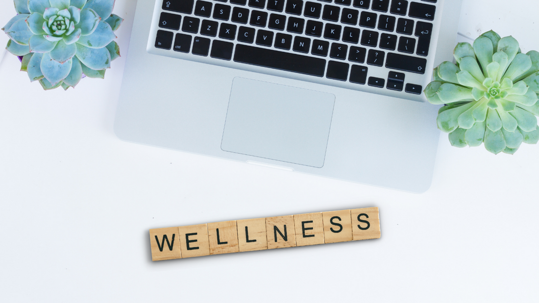 Laptop with succulents and wellness sign on office desk
